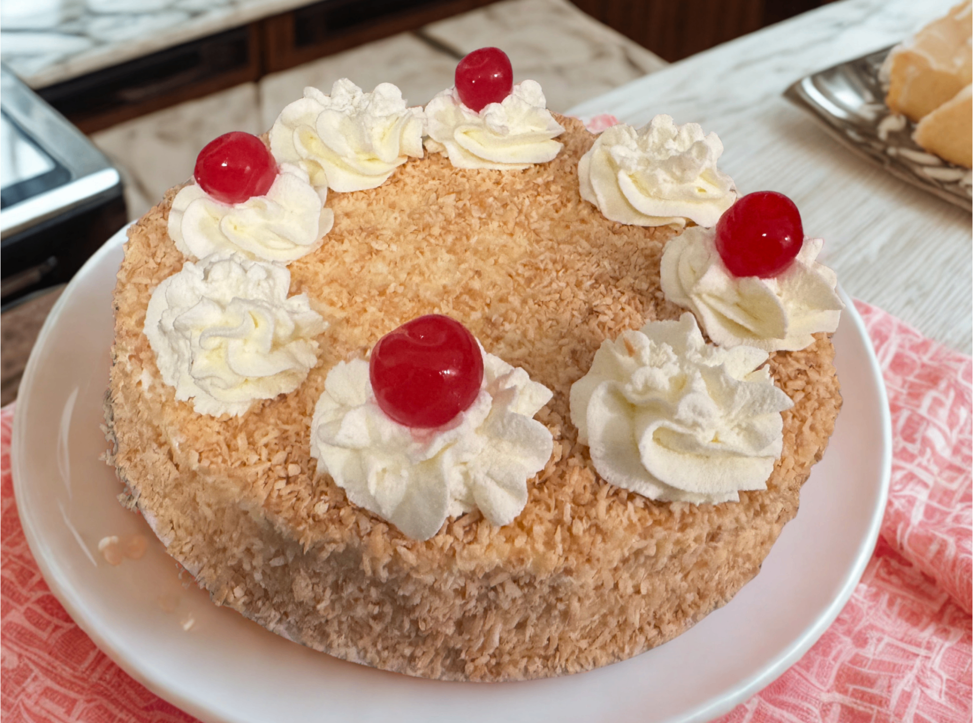 Coconut cake topped with whipped cream rosettes and cherries